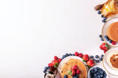 Yaban mersinli krep beyaz arka plan üzerinde çilek, böğürtlen, ahududu, bal ve akçaağaç şurubu ile görev yaptı. Üstten görünüm. Kopya alanı