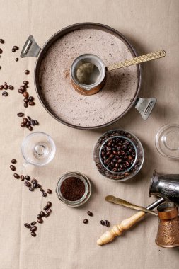 Cam kavanozda taze kahve çekirdekleri ve kahverengi kumaş arkaplanı. Üst manzara, düz uzanma