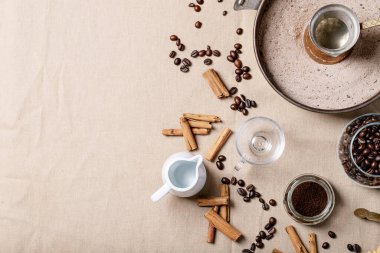 Cam kavanozda taze kahve çekirdekleri ve kahverengi kumaş arkaplanı. Üst manzara, düz uzanma
