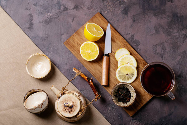 Black tea in glass cup served with fresh lemons over a brown texture background. Top view. Copy Space