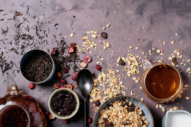 Seramik kasedeki granola kahvaltısı taze süt, kızılcık reçeli ve kahverengi desenli siyah çay ile servis edilir. Üst Görünüm