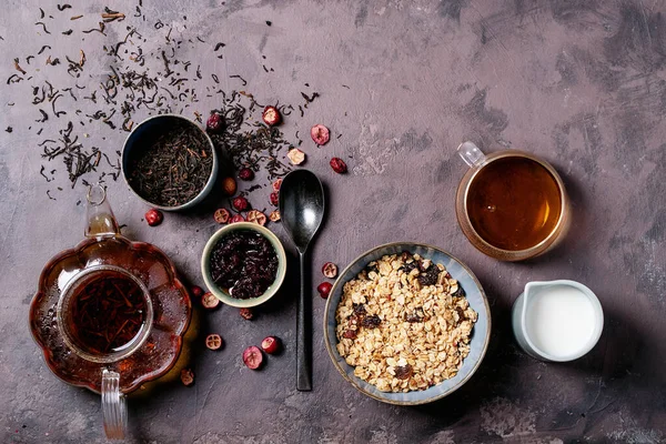 格拉诺拉早餐在陶瓷碗与新鲜牛奶 覆盆子果酱和红茶的褐色质感背景 顶视图 — 图库照片