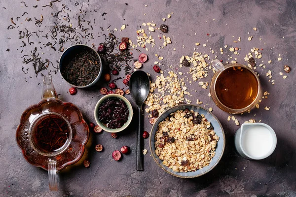 格拉诺拉早餐在陶瓷碗与新鲜牛奶 覆盆子果酱和红茶的褐色质感背景 顶视图 — 图库照片