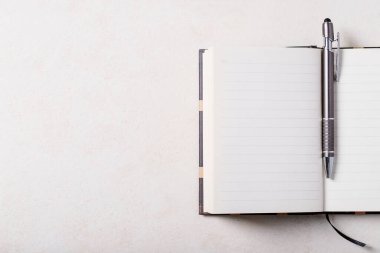 Not defteri olan bir çalışma yeri, beyaz arka planda bir kalem. Üst manzara, düz yatış. Uzayı kopyala Kavram