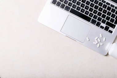 Beyaz arka planda dizüstü bilgisayarı ve antidepresanları olan bir iş yeri. Üst manzara, düz yatış. Uzayı kopyala Kavram