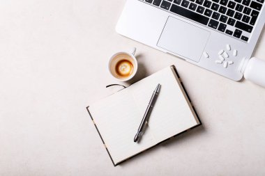 Not defteri, kalem, dizüstü bilgisayar, antidepresanlar ve beyaz arka planda bir fincan kahve olan bir çalışma yeri. Üst manzara, düz yatış. Uzayı kopyala Kavram