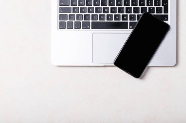 Akıllı telefonu olan bir iş yeri, beyaz arka planda dizüstü bilgisayarı olan. Üst manzara, düz yatış. Uzayı kopyala Kavram