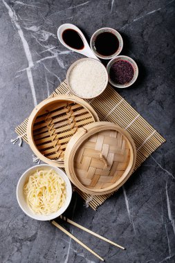 Teriyaki soslu erişte ve pilav, soya sosu, ahşap buharlı buhar ve siyah desenli yemek çubukları. Üst manzara, düz yatış. Boşluğu kopyala