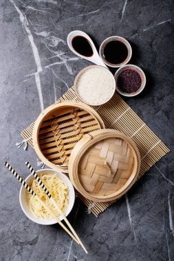 Teriyaki soslu erişte ve pilav, soya sosu, ahşap buharlı buhar ve siyah desenli yemek çubukları. Üst manzara, düz yatış. Boşluğu kopyala