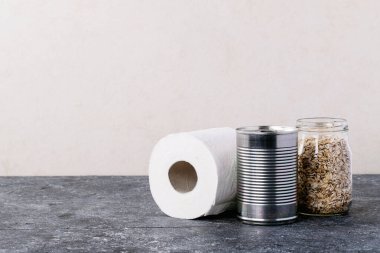 Metal kutularda konserve yiyecekler, yulaf, pirinç, çay ve makarna beyaz doku arka planında cam kavanozlarda. Uzayı kopyala Gıda arzı kavramı