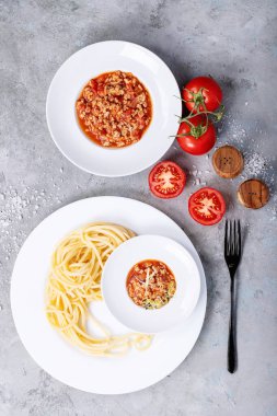 Pişmiş spagetti bolonez, siyah biberli ve beyaz desenli beyaz seramik tabakta saslt. Üst manzara, düz yatış. Boşluğu kopyala