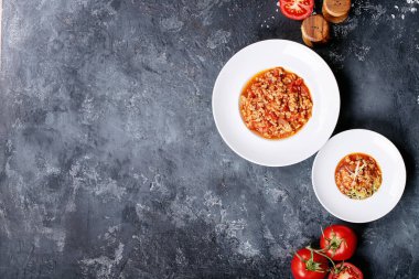 Pişirilmiş spagetti bolonez, siyah doku arka planında beyaz seramik tabakta karabiber ve saslt ile servis edilir. Üst manzara, düz yatış. Boşluğu kopyala