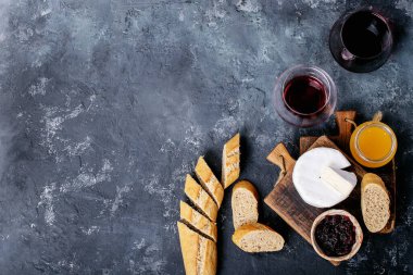 Bir bardak kırmızı şarap, peynirli camembert peyniri, bal, reçel ve Fransız ekmeği ile servis edilir. Üst manzara, düz yatış. Boşluğu kopyala