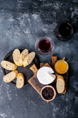 Bir bardak kırmızı şarap, peynirli camembert peyniri, bal, reçel ve Fransız ekmeği ile servis edilir. Üst manzara, düz yatış. Boşluğu kopyala
