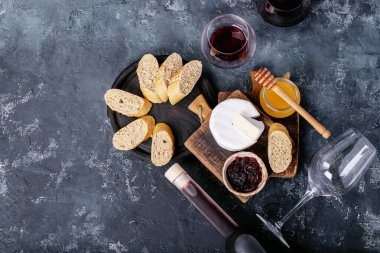 Bir bardak kırmızı şarap, peynirli camembert peyniri, bal, reçel ve Fransız ekmeği ile servis edilir. Üst manzara, düz yatış. Boşluğu kopyala