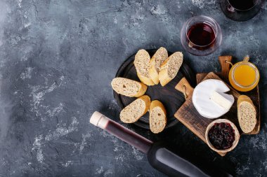 Bir bardak kırmızı şarap, peynirli camembert peyniri, bal, reçel ve Fransız ekmeği ile servis edilir. Üst manzara, düz yatış. Boşluğu kopyala
