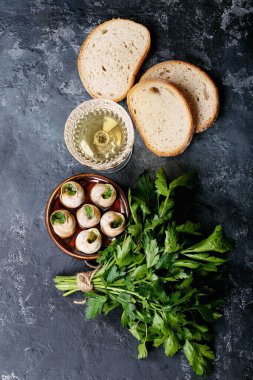 Sarımsaklı tereyağlı fırında salyangoz ve seramik kapta taze otlar. Üst manzara, düz yatış. Boşluğu kopyala