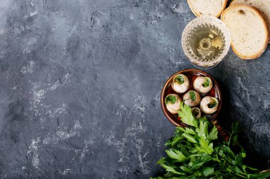 Sarımsaklı tereyağlı fırında salyangoz ve seramik kapta taze otlar. Üst manzara, düz yatış. Boşluğu kopyala