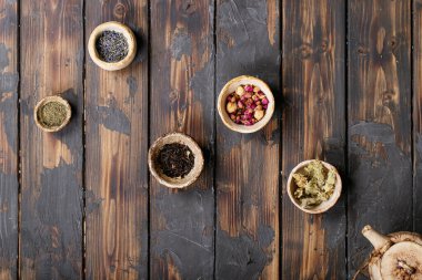 Seramik fincanlarda siyah ve yeşil çay seramik çaydanlık ve kahverengi ahşap zemin üzerinde gül yaprakları. Üst Manzara. Boşluğu Kopyala