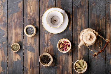 Seramik fincanlarda siyah ve yeşil çay seramik çaydanlık ve kahverengi ahşap zemin üzerinde gül yaprakları. Üst Manzara. Boşluğu Kopyala