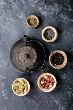 Siyah metal çaydanlık ve koyu dokuda gül yapraklarıyla seramik bir fincanda siyah ve yeşil çay. Üst Manzara. Boşluğu Kopyala