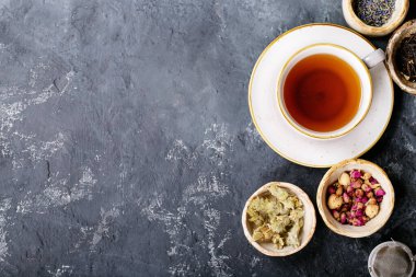 Siyah metal çaydanlık ve koyu dokuda gül yapraklarıyla seramik bir fincanda siyah ve yeşil çay. Üst Manzara. Boşluğu Kopyala