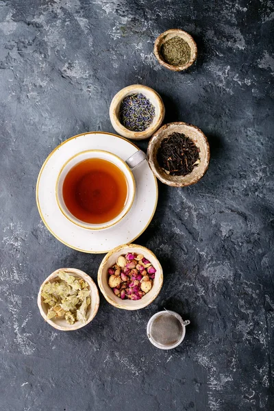 红茶和绿茶在陶瓷杯与黑色金属茶壶和玫瑰花瓣在黑暗的纹理背景 顶部视图 复制空间 — 图库照片
