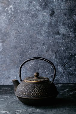 Siyah metal çaydanlık ve koyu dokuda siyah çay.