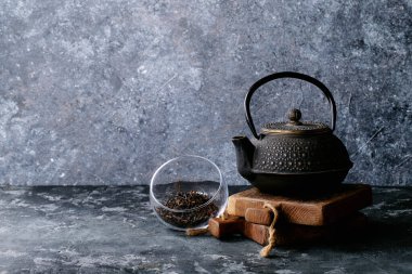 Siyah metal çaydanlık ve koyu dokuda siyah çay.