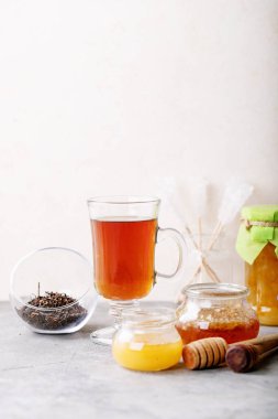 Beyaz desenli arka planda bal ile servis edilen bir bardak siyah çay.