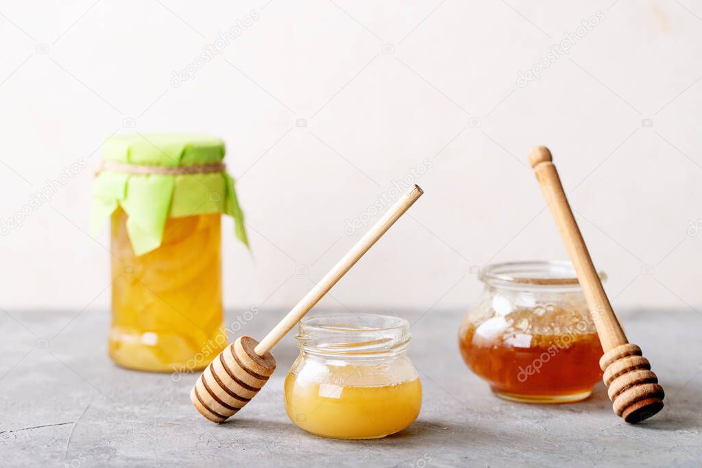 Glass cup of black tea served with honey over white texture background