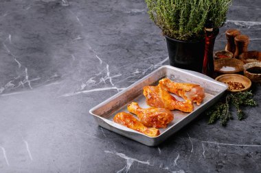 Taze kekik, tuz, biber taneleri, kekik ve barbekü soslu çiğ tavuk budu.