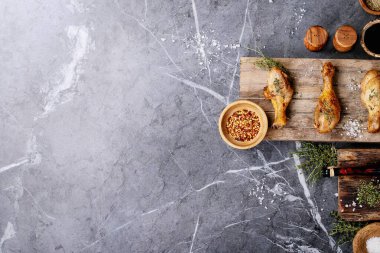 Izgara acılı tavuk budu, taze kekik, tuz, acı biber taneleri, kekik ve barbekü sosu ile koyu dokuma arka planda. Üst manzara, düz yatış. Boşluğu kopyala