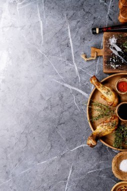 Izgara acılı tavuk budu, taze kekik, tuz, acı biber taneleri, kekik ve barbekü sosu ile koyu dokuma arka planda. Üst manzara, düz yatış. Boşluğu kopyala