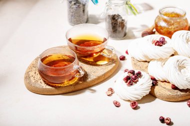 Cam bardakta çay, pavlova tatlısı ve beyaz desenli yaban mersini ile servis edilir.