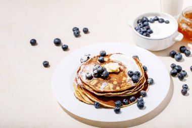 Beyaz arka planda bal ve yaban mersinli krep yığını..