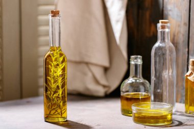 Cam şişelerde biberiyeli zeytinyağı koyu ahşap arka planda. Üst manzara, düz yatış. Boşluğu kopyala