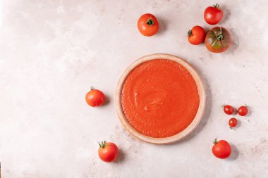 Beyaz dokuma arka planında taze domateslerle servis edilen ev yapımı domates çorbası.