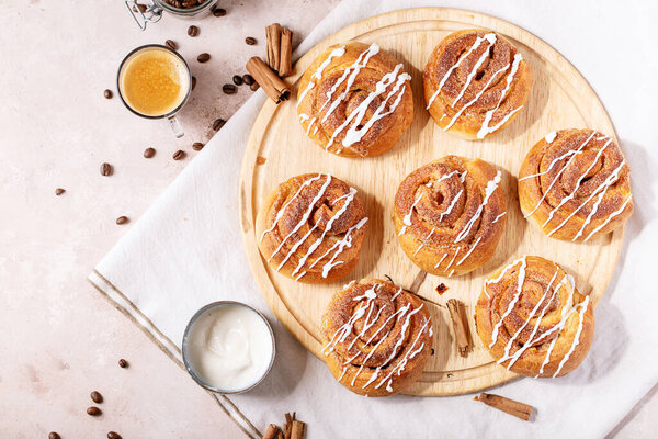 Baked cinnamon buns served with cinnamon and coffee over white texture background. Top view, flat lay. Copy space