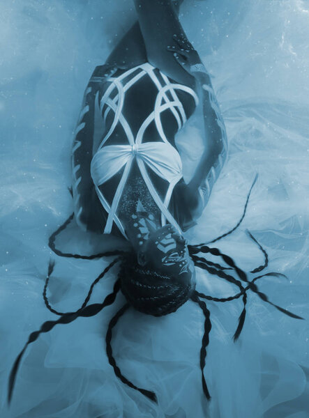 The girl is an alien, the keeper of the universe, lying on the floor. Art on the body fluorescent paints. Photosession with ultraviolet light. Hairstyle with braids. Beautiful, sexy costume