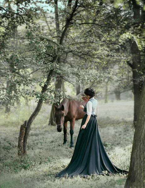 公主穿着老式的连衣裙 长着火车 带着一匹马走路 一张没有脸的黑发女孩的照片 背景是梦幻般的 一个神话般的森林 — 图库照片