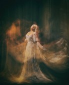 Sklavin, Dienerin der Finsternis... Königin Albino. ein blondes Mädchen, wie ein Gespenst, in einem weißen Vintage-Kleid, in einem schwarzen Zimmer, eine gotische, künstlerische Fotografie einer Zauberin und Magierin. Maria Magdalene