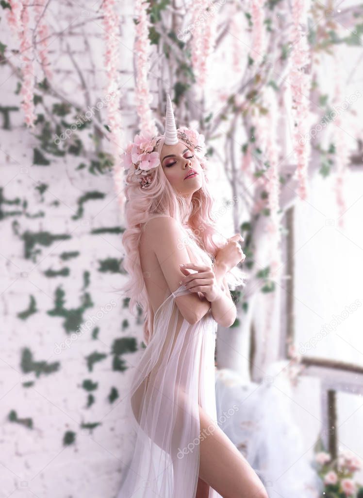 Wonderful creation, the girl is a unicorn in light, white, slightly transparent attire. The background is a bright room that is overgrown with plants, moss, ivy, trees and flowers. Artistic Photo