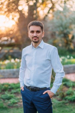 Bir kıl ve kısa saç kesimi olan esmer bir adam portresi. Acımasız sakal. Mavi pantolon ve bir gömlek, bir gün batımının arka ışık şık bir adam