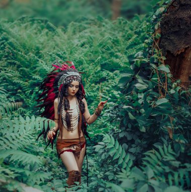 Yerli Kızılderili karanlık ormanlarda çalılıkları içinde yürür. Prenses Pocahontas. Etnik avcı deri elbiseli kız. Sanatsal fotoğraf