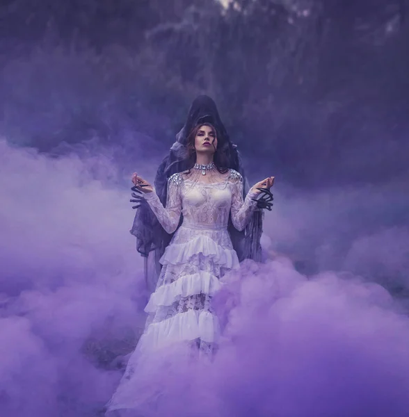 一个黑色的皇后 红色的嘴唇穿着白色的复古连衣裙和一条银色项链在一个摄魂怪的胳膊上站在紫色的薄雾与她的眼睛关闭 万圣节服装的想法 艺术哈利波特 — 图库照片