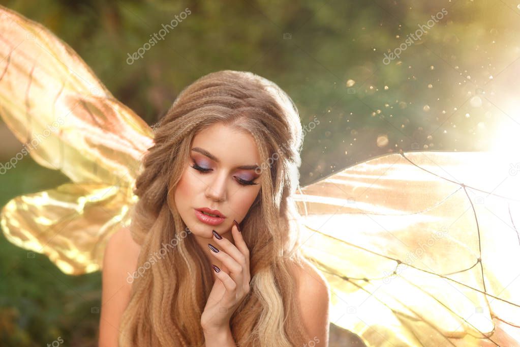 gorgeous young enchantress with transparent wings and blond hair with beautiful appearance, model posing with closed eyes, cool summer photo, fairytale hero with bare shoulders in the sun.