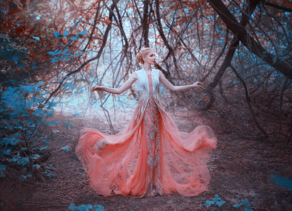 Delightful queen blond elf standing in the forest near the branches of trees that touch the ground, wearing a light amazing peach pink tender dress, throws it down, flying clothing fluttering.
