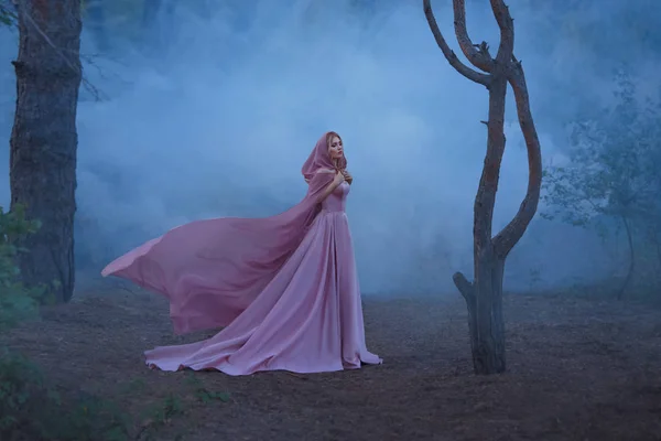 parlak bir başlık bir başlık ile tutarak harika herbalist enchantress bir pahalı lüks uzun yumuşak pembe elbise giymiş, sarışın saçlı kız sis tam bir karanlık ormanda tek başına ayakta.