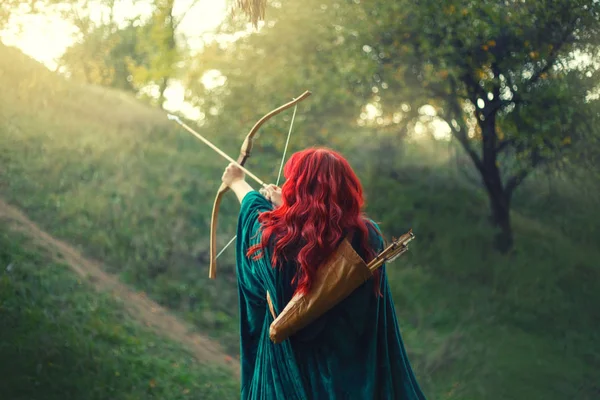 Hermosa cazadora empujando su última luz al sol, esperando la salvación durante el terrible peligro, chica pelirroja lucha por la vida, capa de terciopelo esmeralda, foto sin una cara de la parte posterior — Foto de Stock